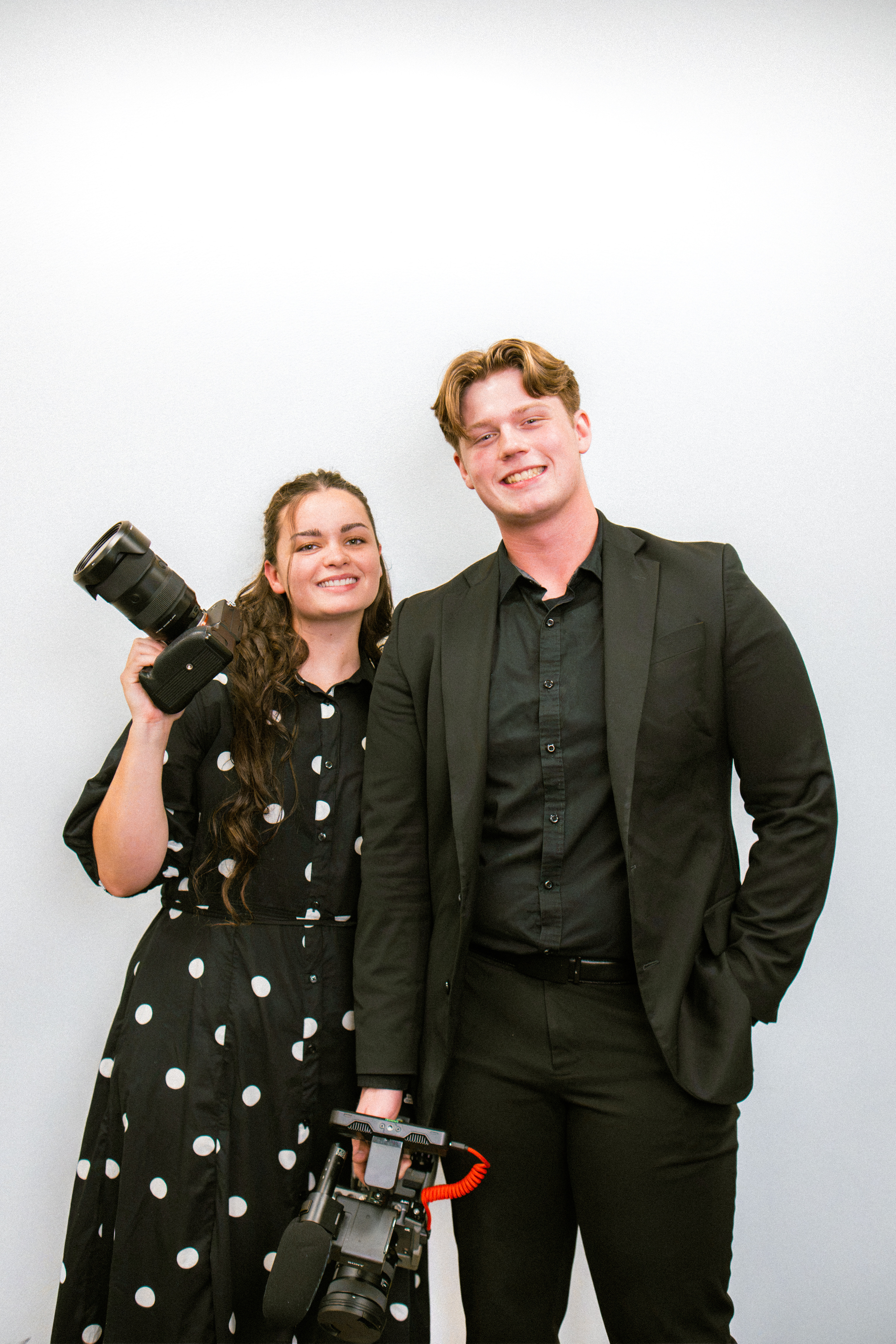 Trey and Gabby Vaughan standing together with their video and photo cameras